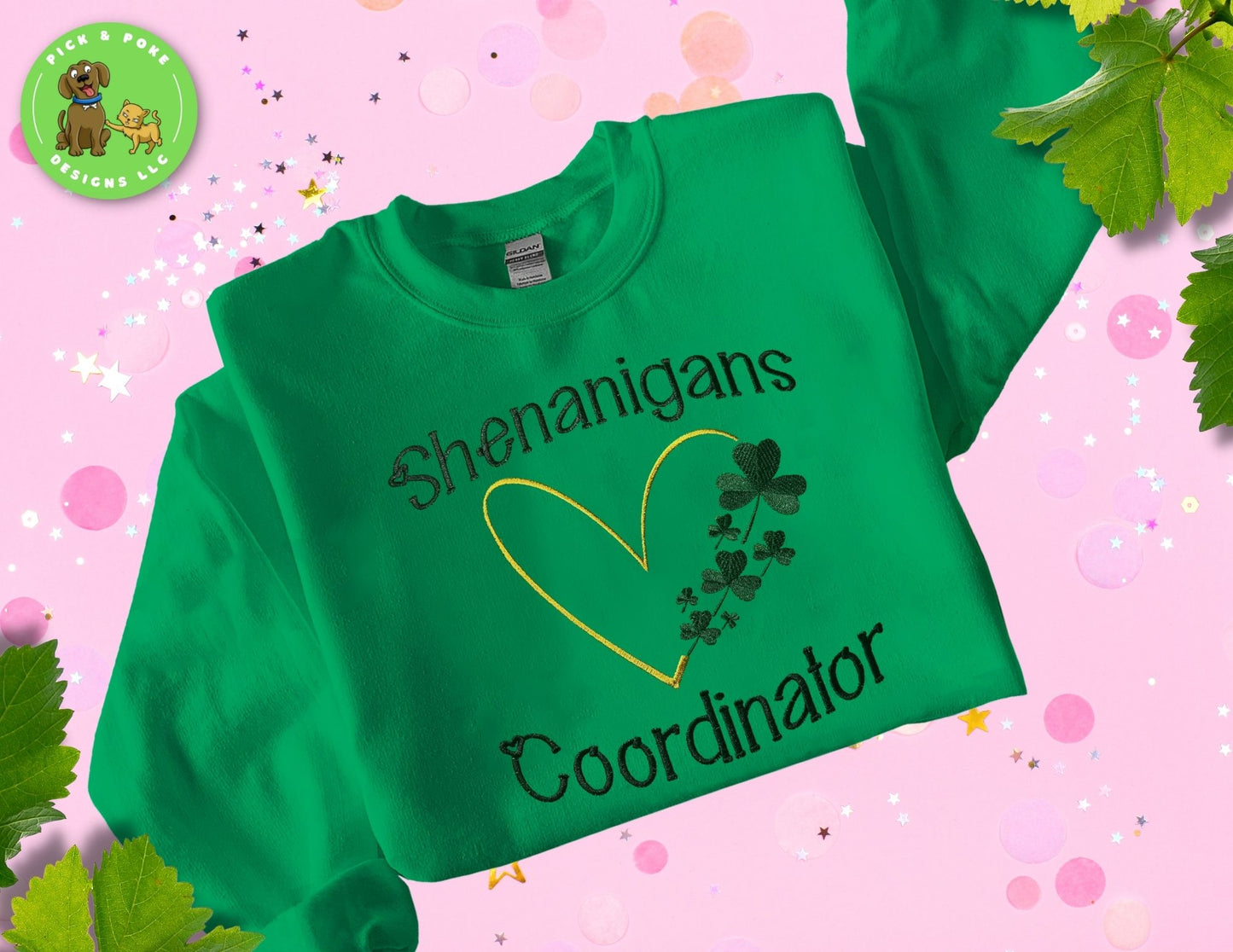 A vibrant green crewneck sweatshirt with gold embroidery featuring the words "Shenanigans Coordinator" and a heart made of clovers. The crewneck is laid out on a pink background, ready to be worn and styled by any fun-loving teacher.